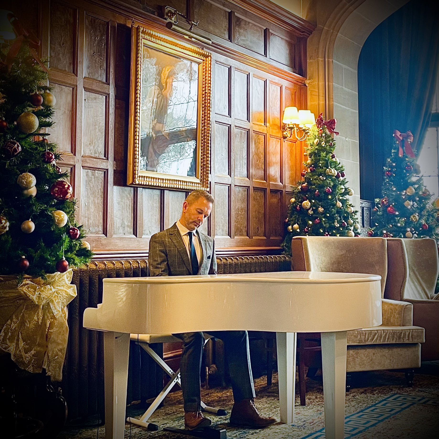 Wedding pianist Craig Smith plays his white baby grand piano for a wedding reception in the Armathwaite Hall Main Hall