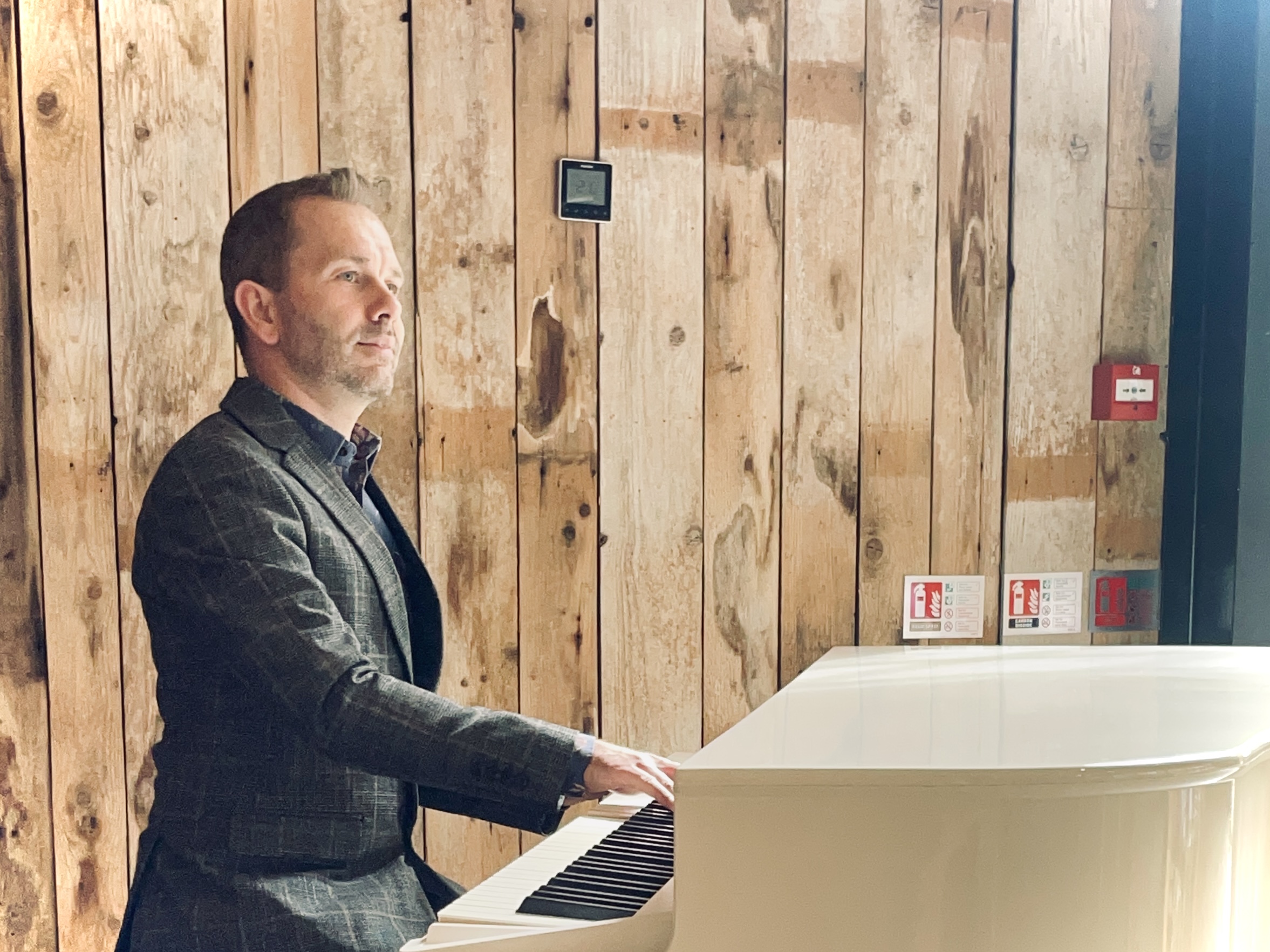 Hidden River Barn wedding pianist performing on his white baby grand piano in the barn