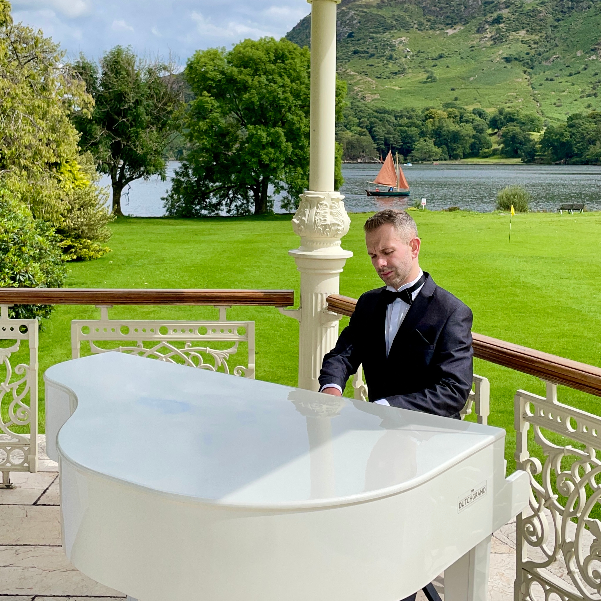 Wedding pianist Craig Smith plays his white baby grand piano for a lakeside Inn on the Lake wedding ceremony
