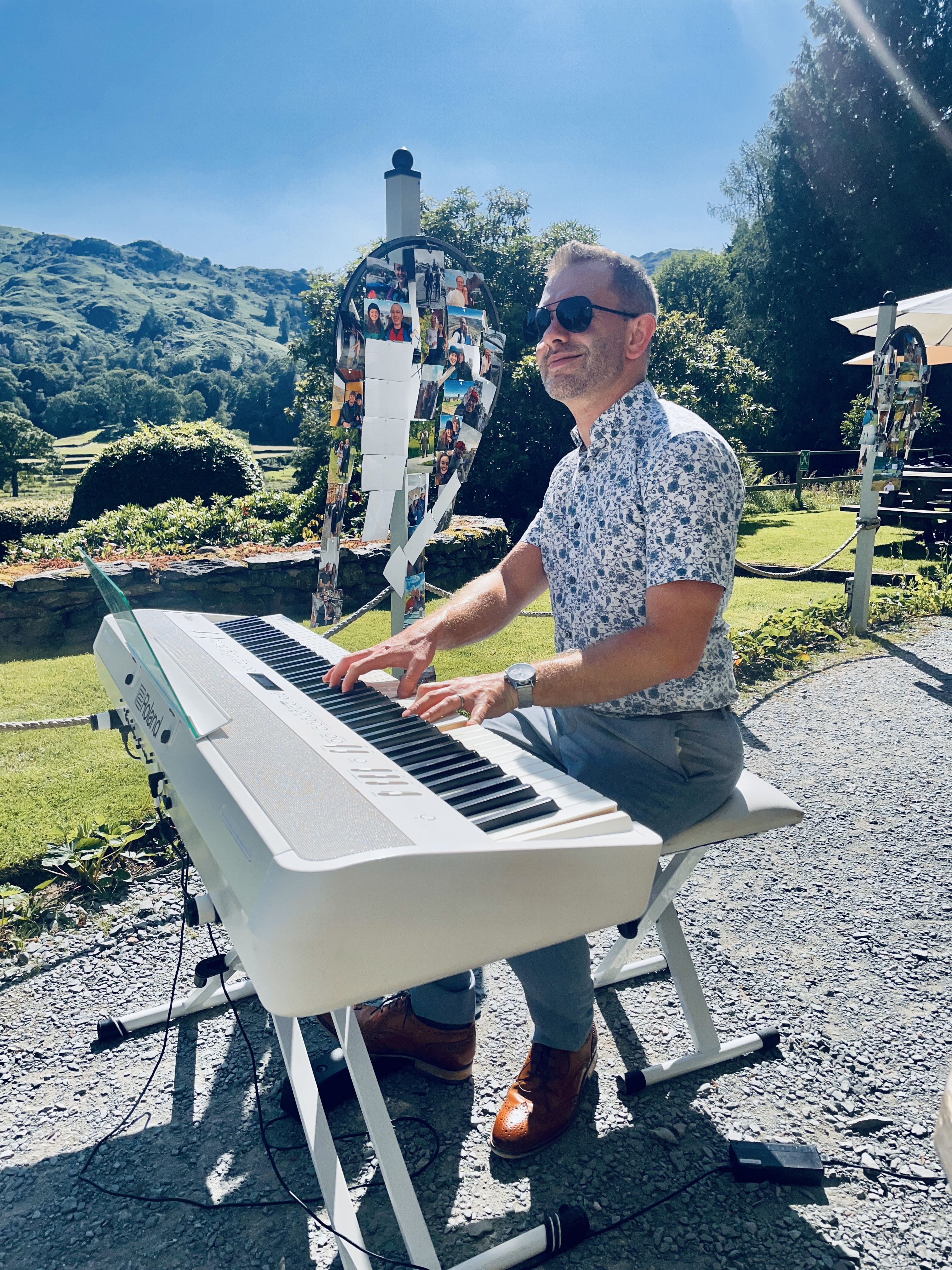 The Lake District Pianist Craig Smith plays piano outside during a sunny Lancrigg wedding reception