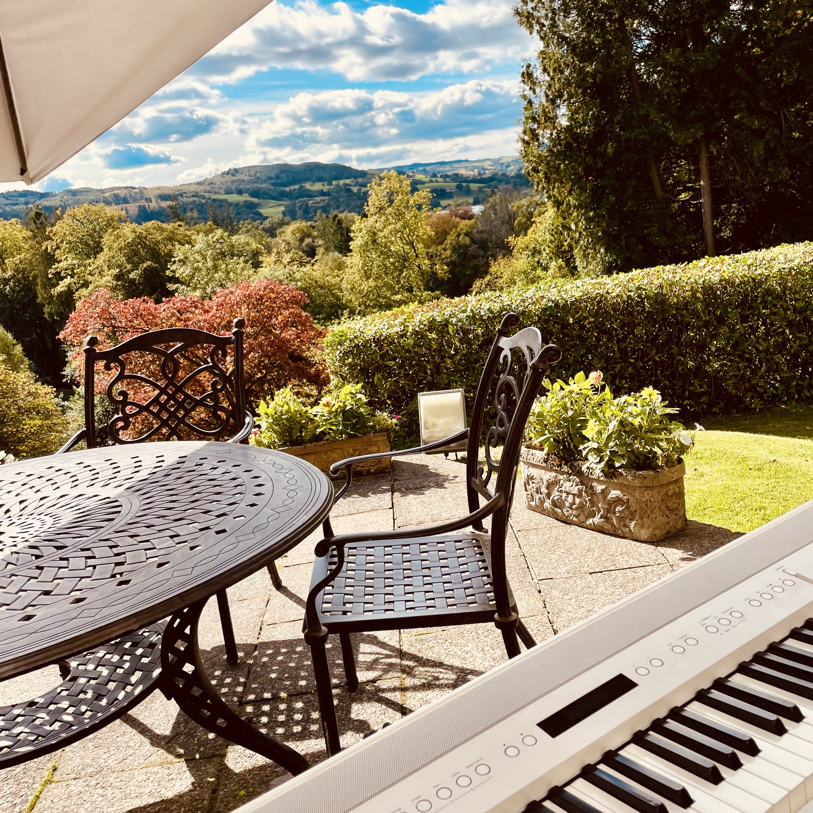 Merewood Country House wedding pianist Craig Smith's white piano set up on a sunny terrace ahead of a drinks reception with lake views